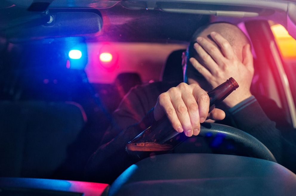 Mann mit Bierflasche am Steuer im Auto